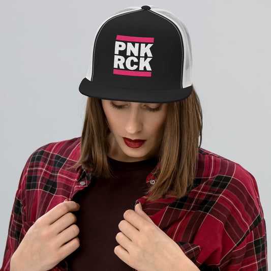 Person wearing a black and white cap with 'PNK ROCK' text, red plaid shirt, and dark lipstick.