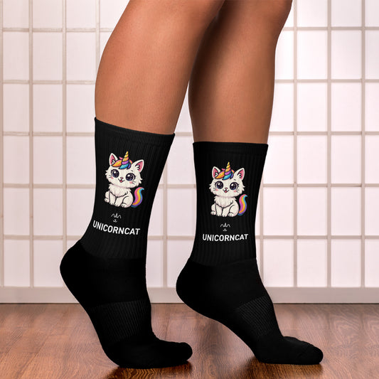 Black socks with unicorn and cat design worn by a person on a tiled floor.