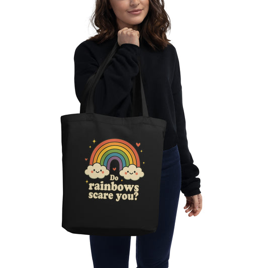 Person holding a black tote bag with a rainbow and cloud design and text.