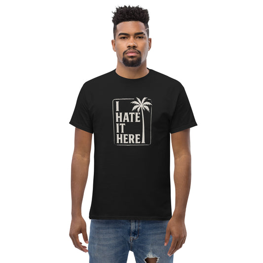 Person wearing a black t-shirt with 'I Hate It Here' text and palm tree graphic on a white background