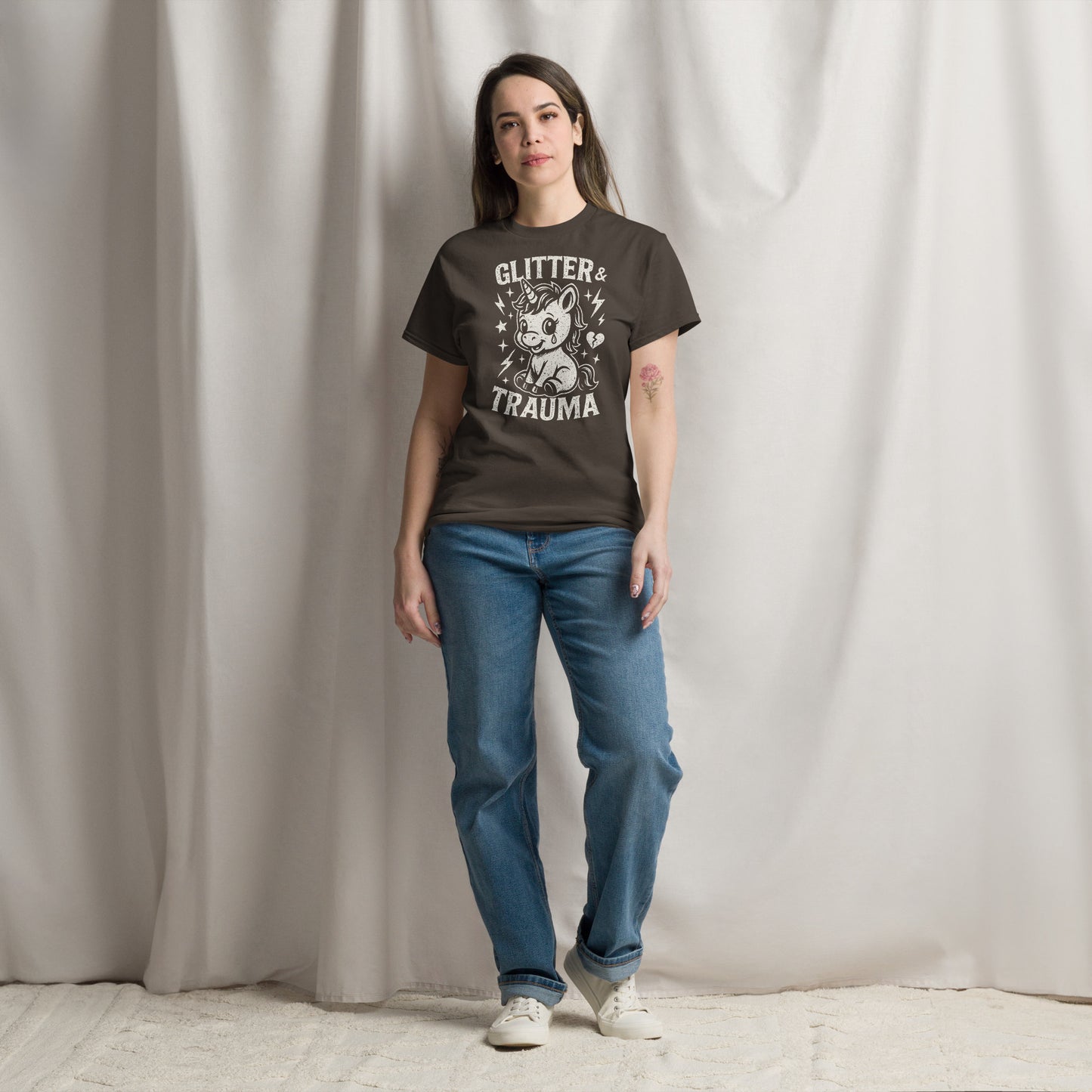 Person wearing a dark t-shirt with graphic design and text, standing against a plain background