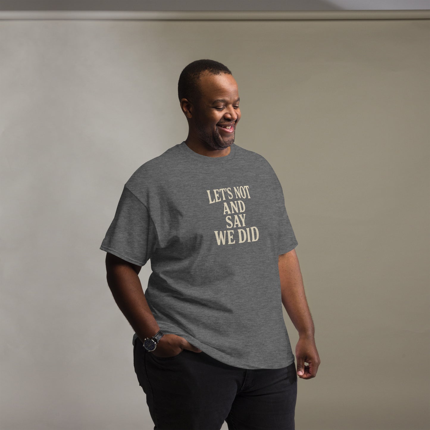 Man wearing a gray t-shirt with text, standing against a plain background