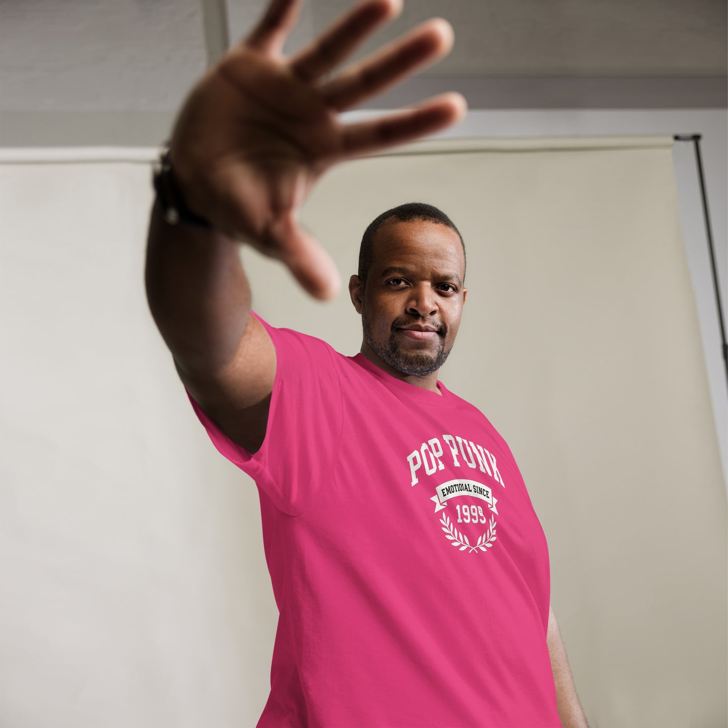 Man wearing a pink 'Pop Forum' t-shirt with his hand outstretched.