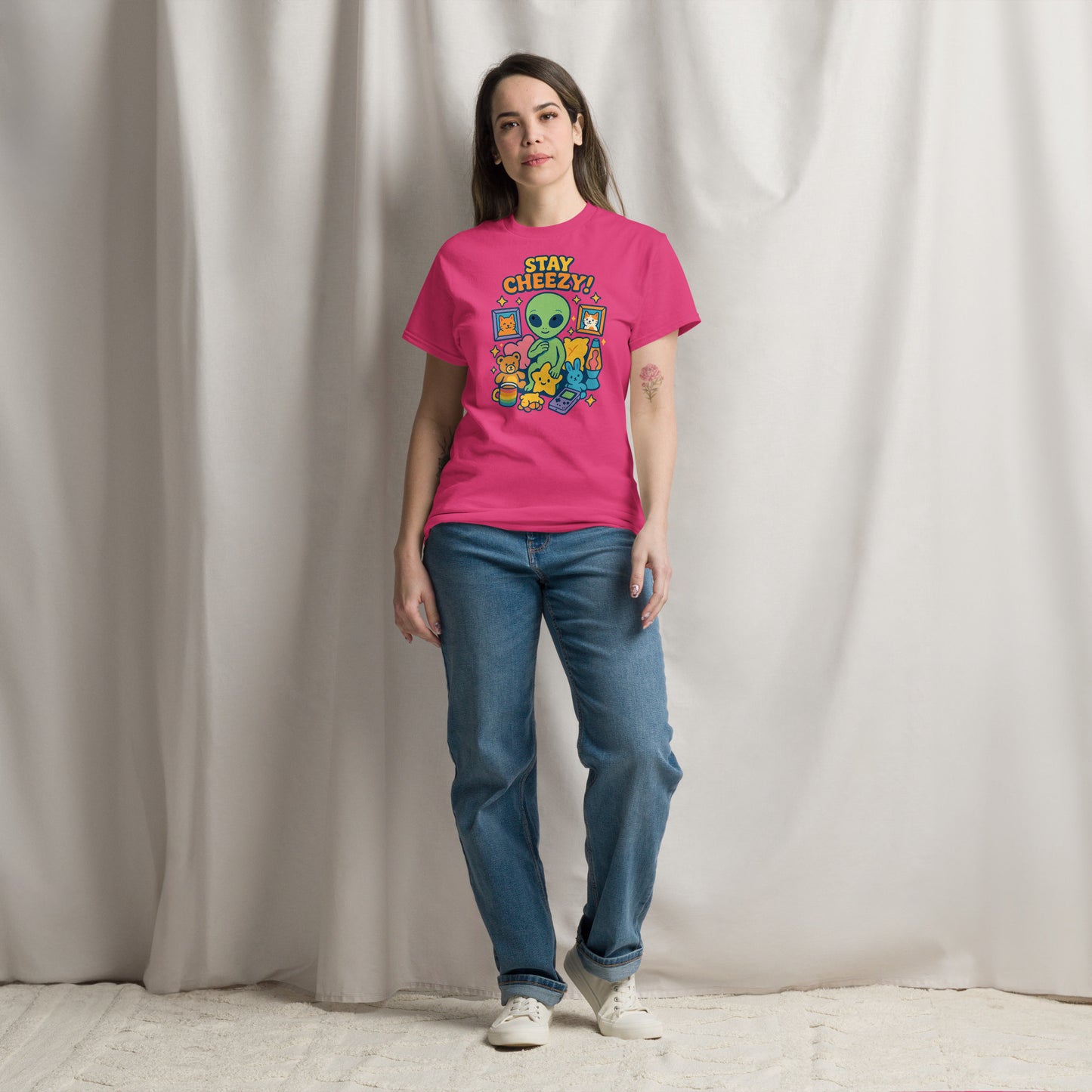 Person wearing a pink t-shirt with a graphic design and text, standing against a plain background