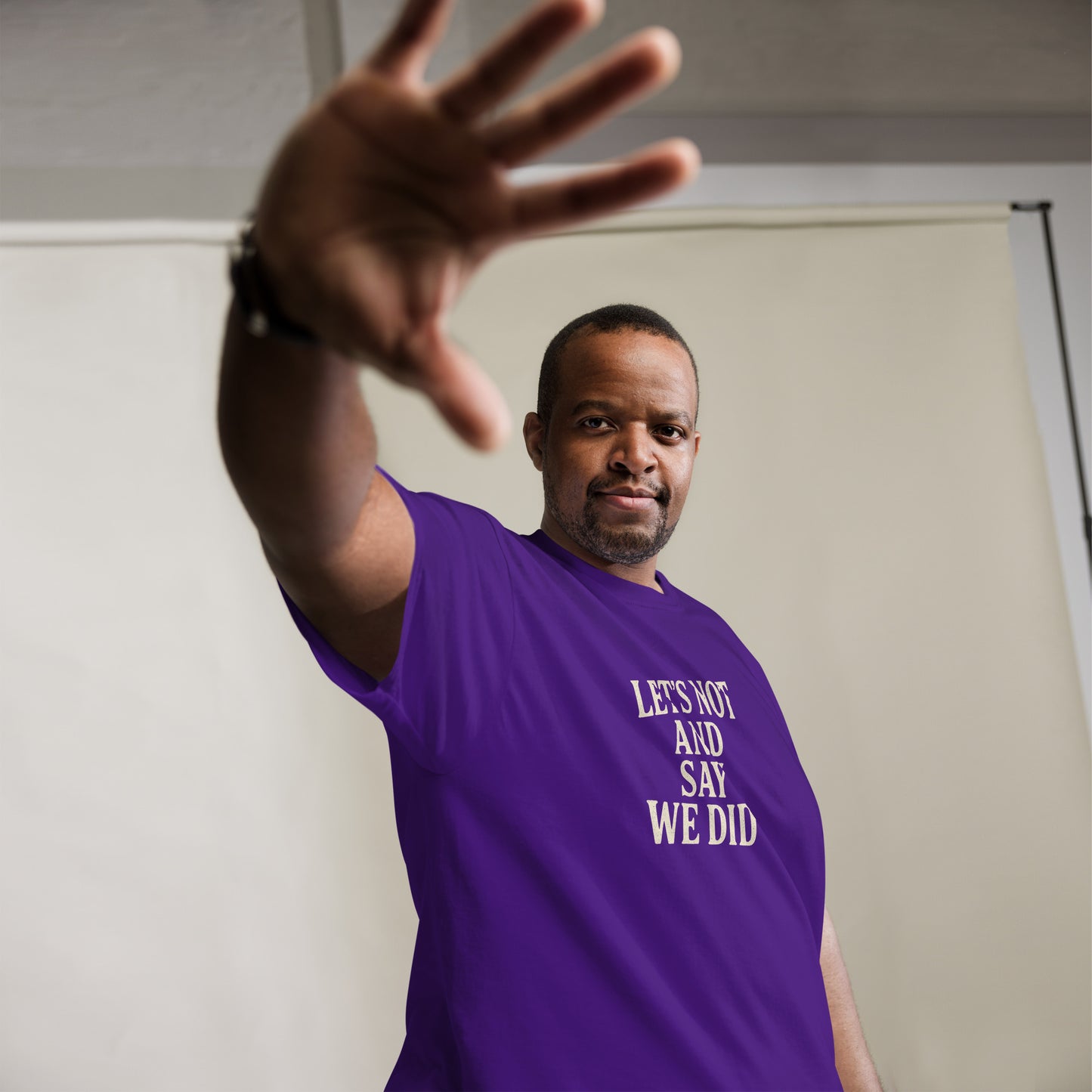 Man wearing a purple t-shirt with text, making a gesture with his hand.