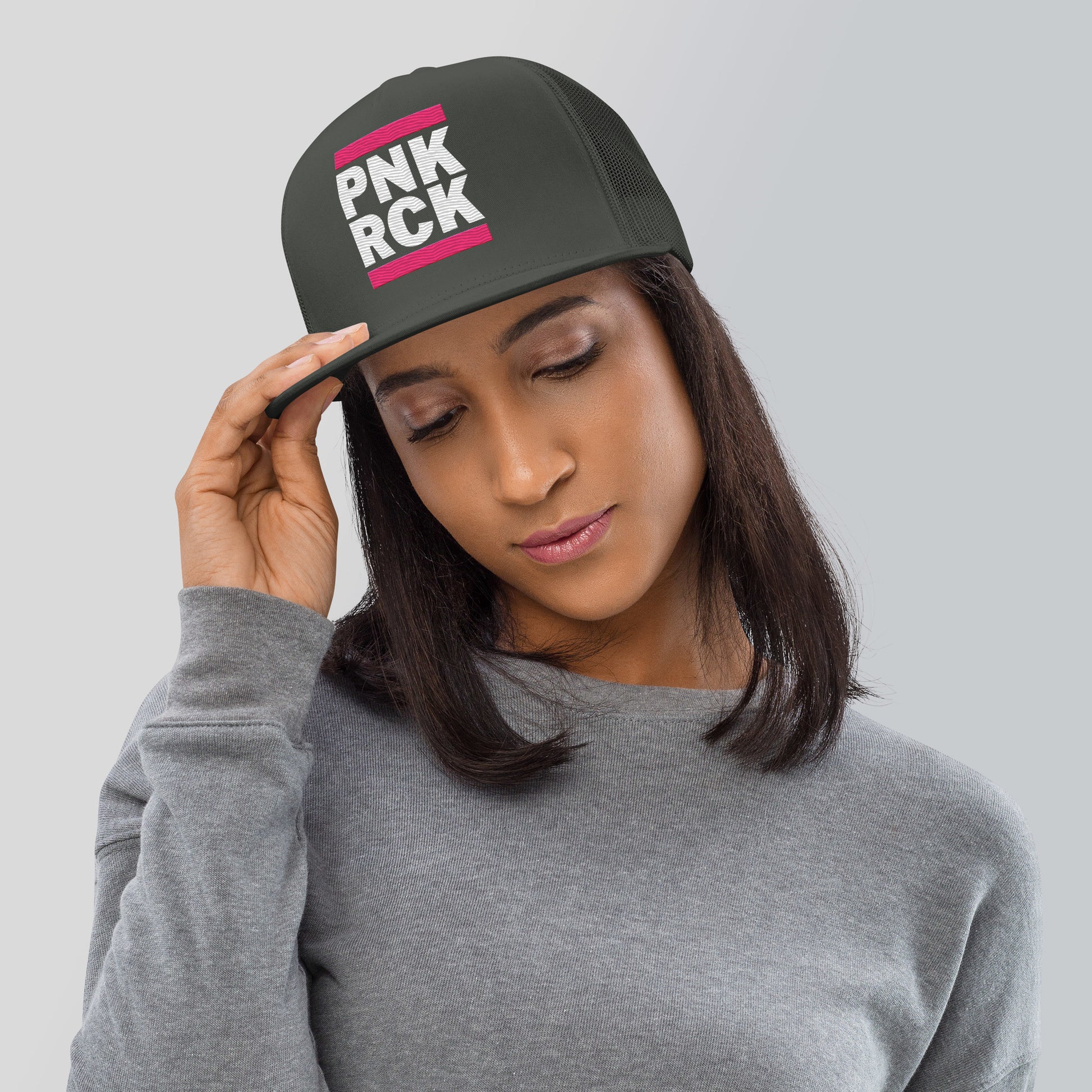 Woman wearing a black cap with 'PNK ROCK' text on a gray background