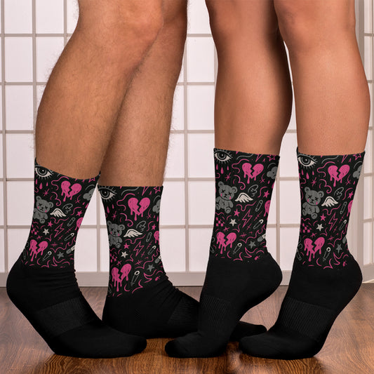 Black socks with pink and gray designs worn by two people on a tiled floor.
