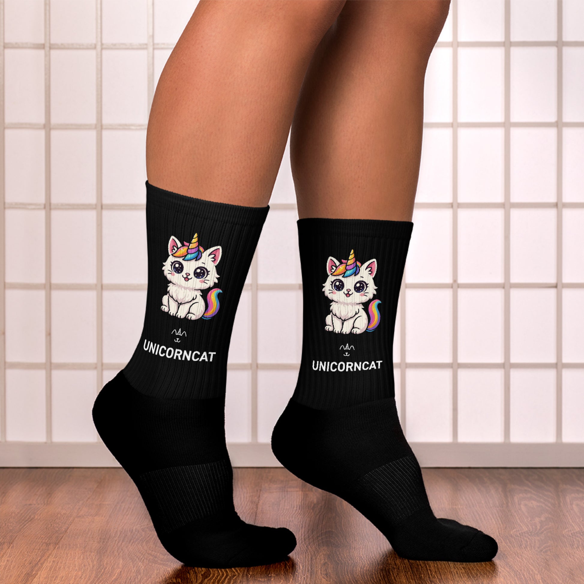 Black socks with unicorn and cat design worn by a person on a tiled floor.