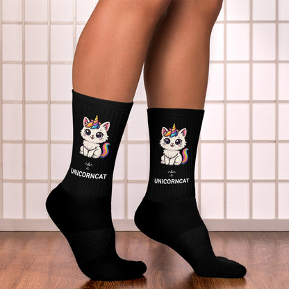 Black socks with unicorn and cat design worn by a person on a tiled floor.