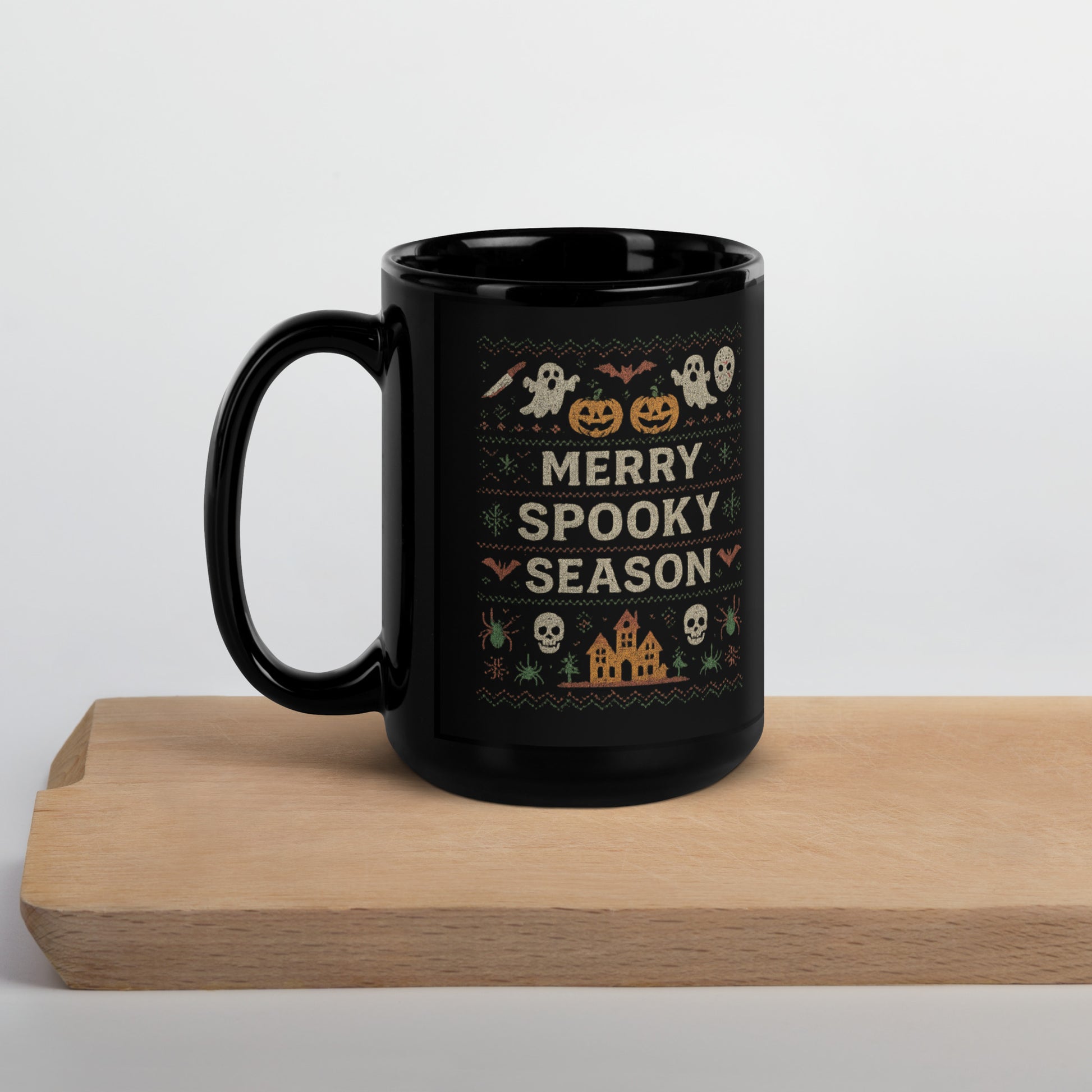 Black mug with Halloween-themed design and 'Merry Spooky Season' text on a wooden surface.
