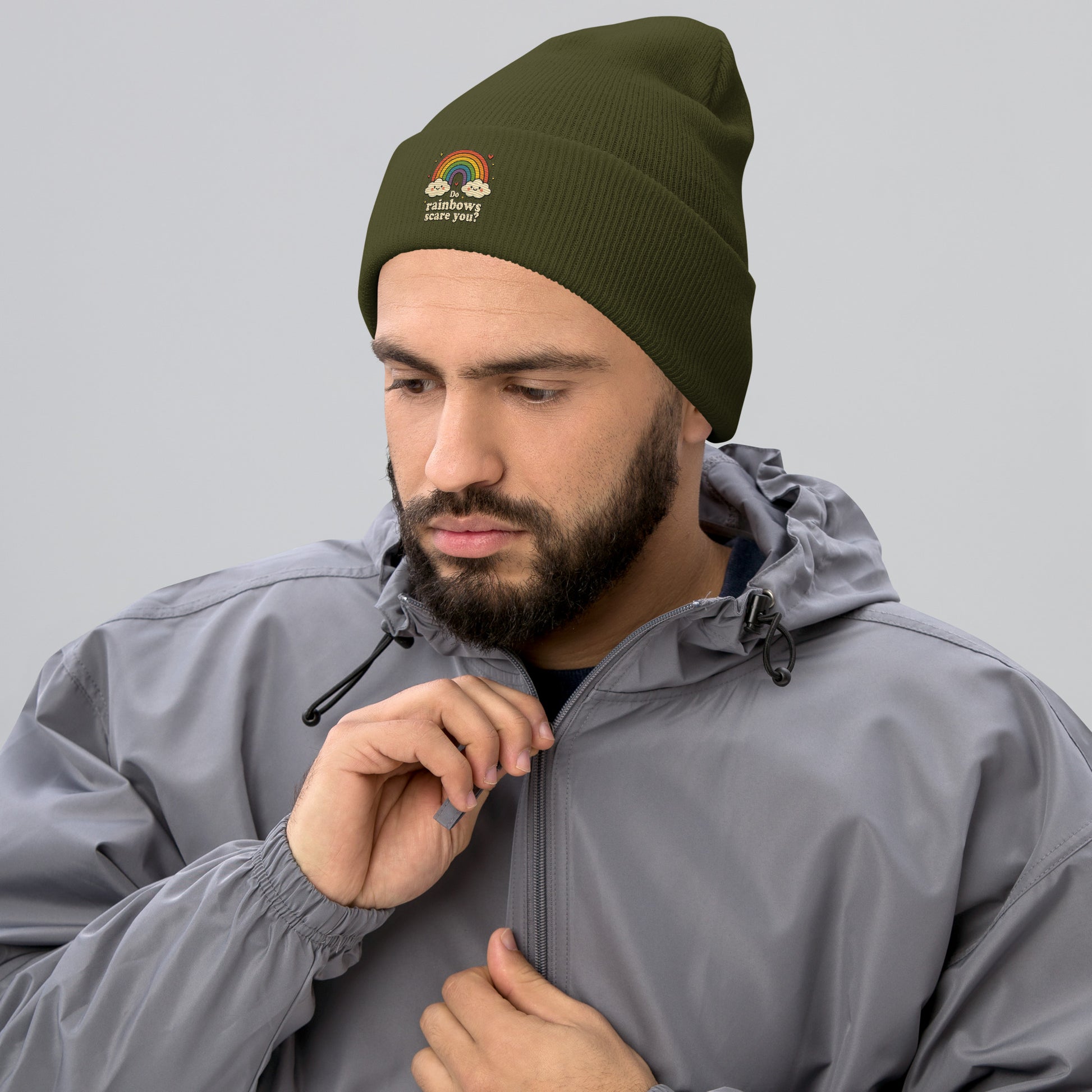 Man wearing a green beanie with embroidery and a gray jacket on a light gray background
