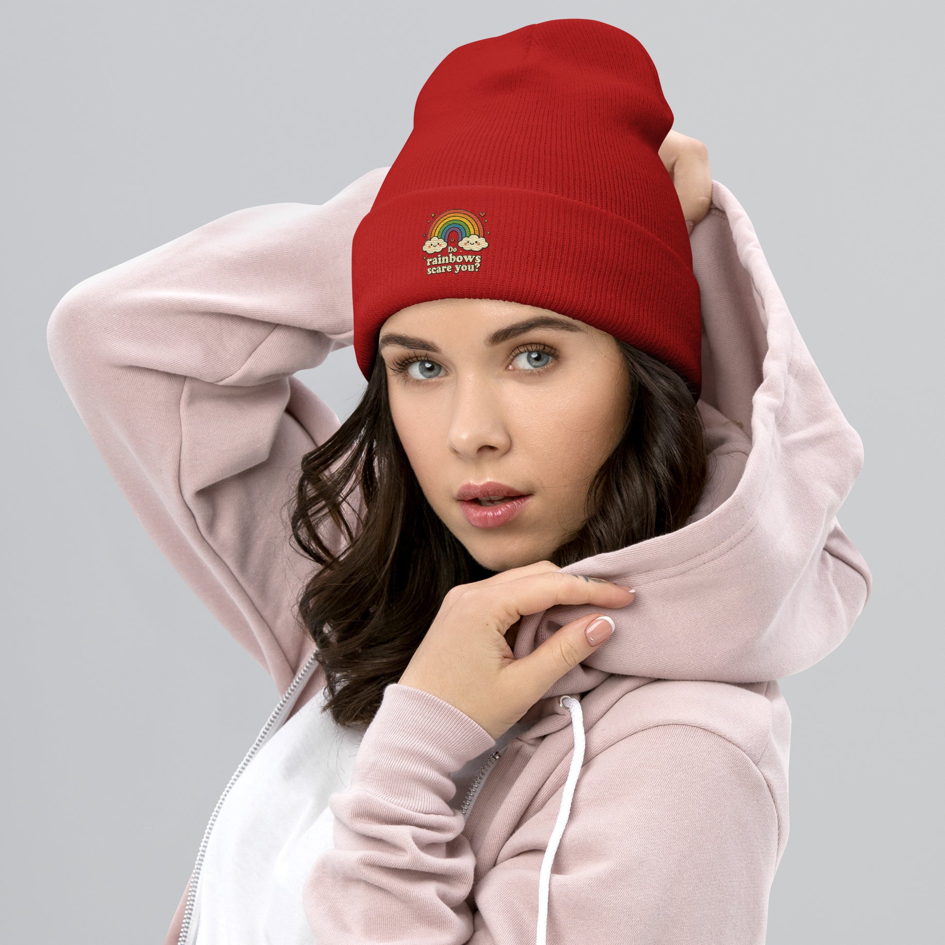 Woman wearing a red beanie with text and a pink hoodie on a gray background