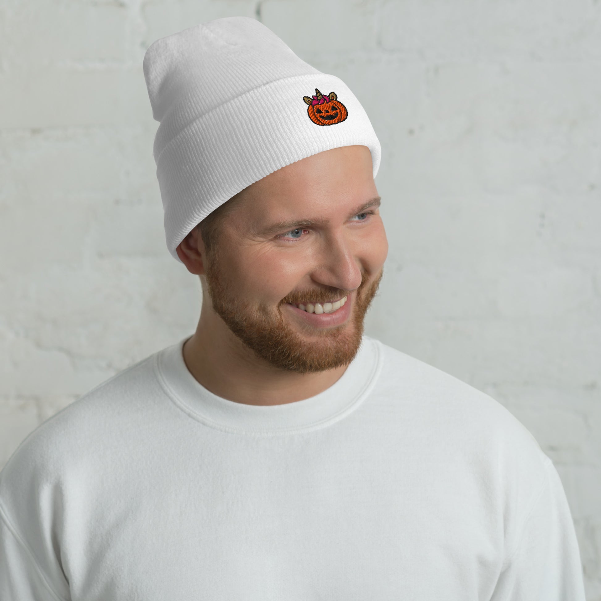 Man wearing a white beanie with a small logo against a light gray background