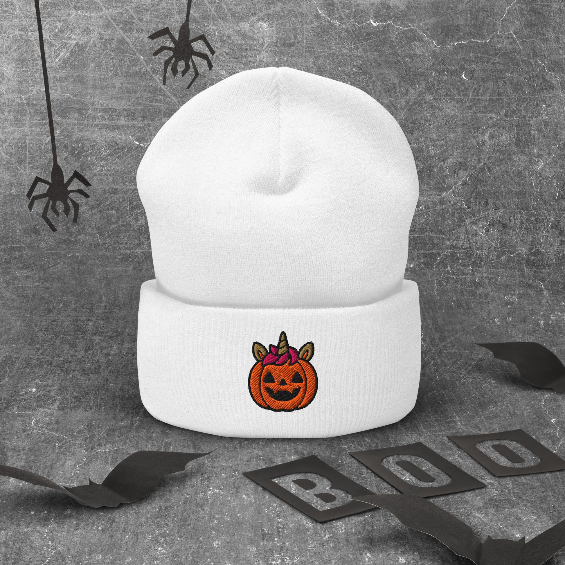 White beanie with a Halloween-themed pumpkin design on a gray background with spider webs and 'BOO' letters.