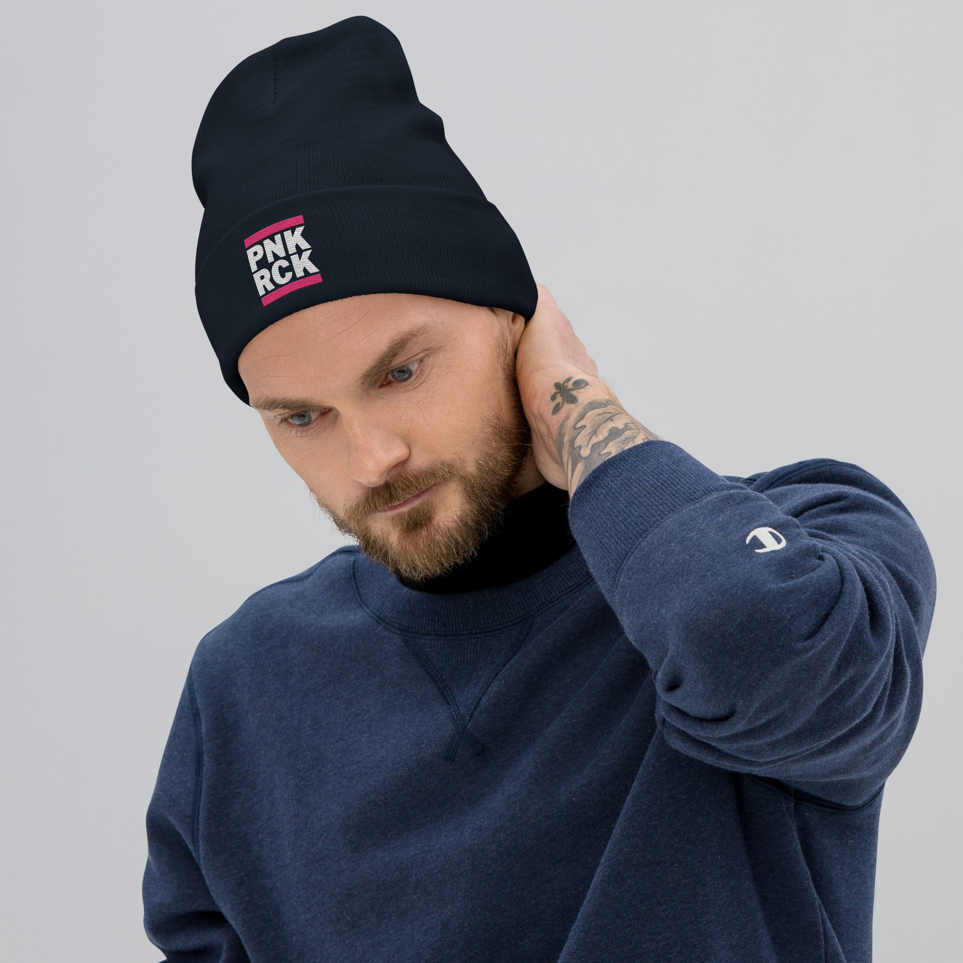 Man wearing a black beanie with 'PNK ROCK' text and a blue sweatshirt on a gray background