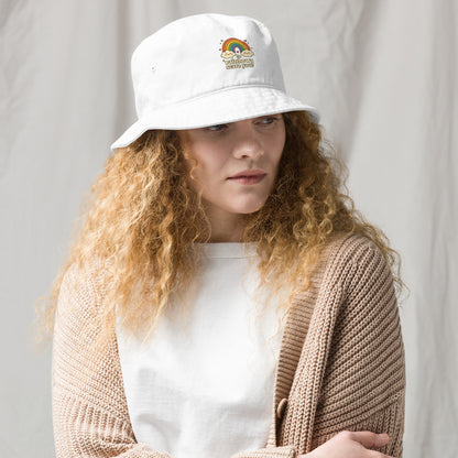 Person wearing a white bucket hat with a logo against a plain background