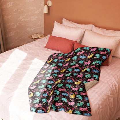 Colorful dinosaur-patterned blanket on a bed with pink bedding and pillows.