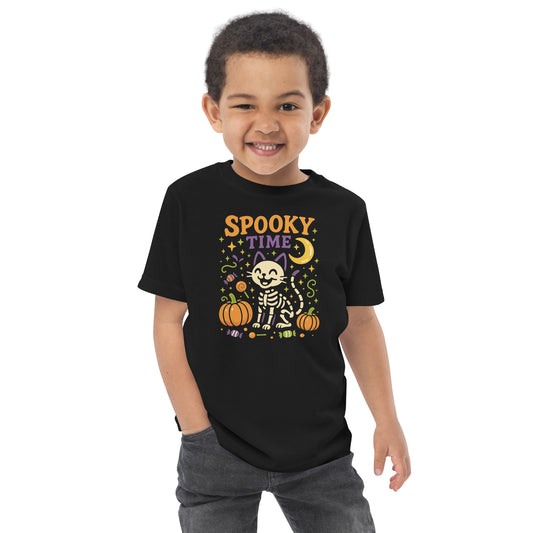 child wearing black shirt with the text "Spooky Time" and a skeleton cat next to pumpkins