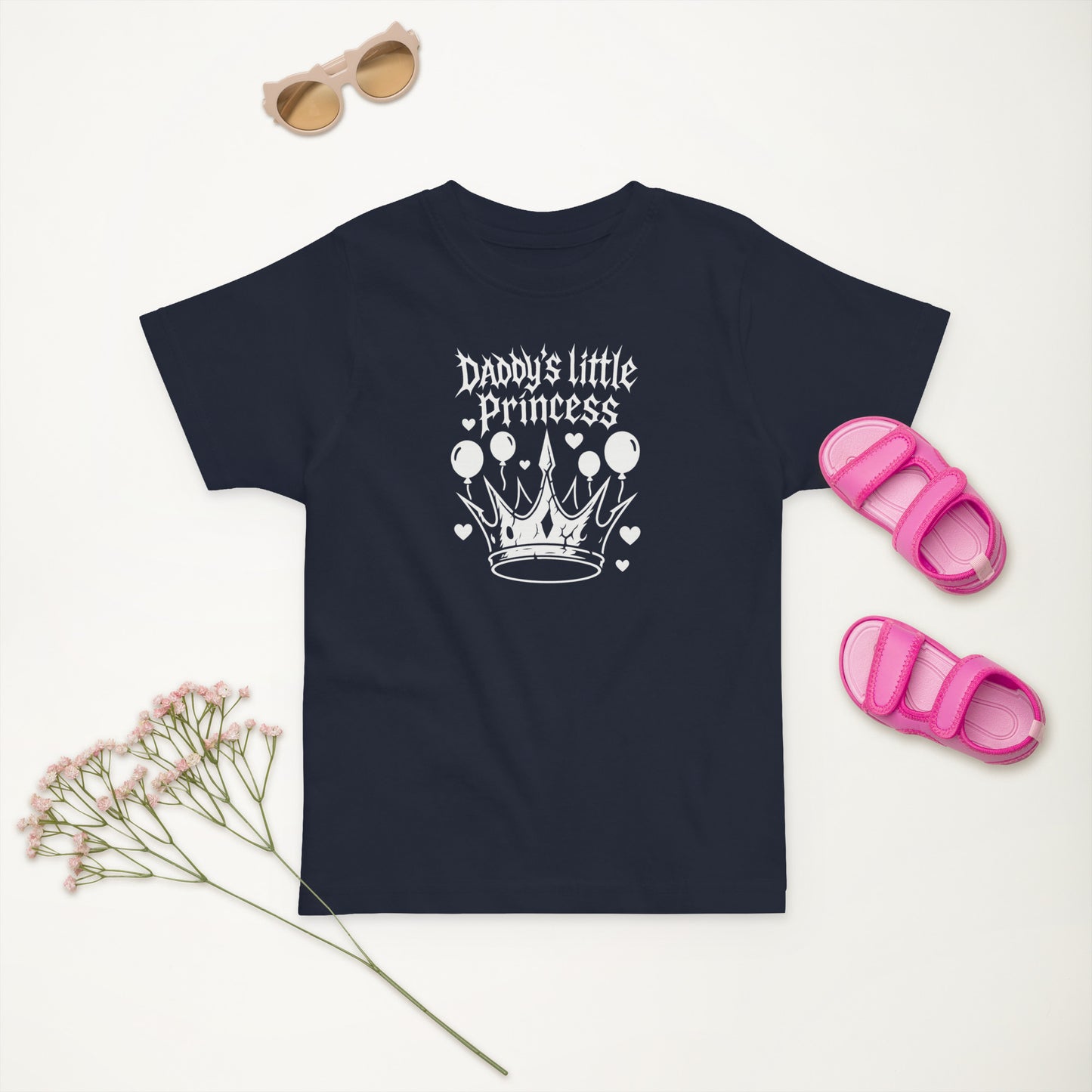Navy blue t-shirt with 'Daddy's little Princess' design, sunglasses, sandals, and flowers on a light background