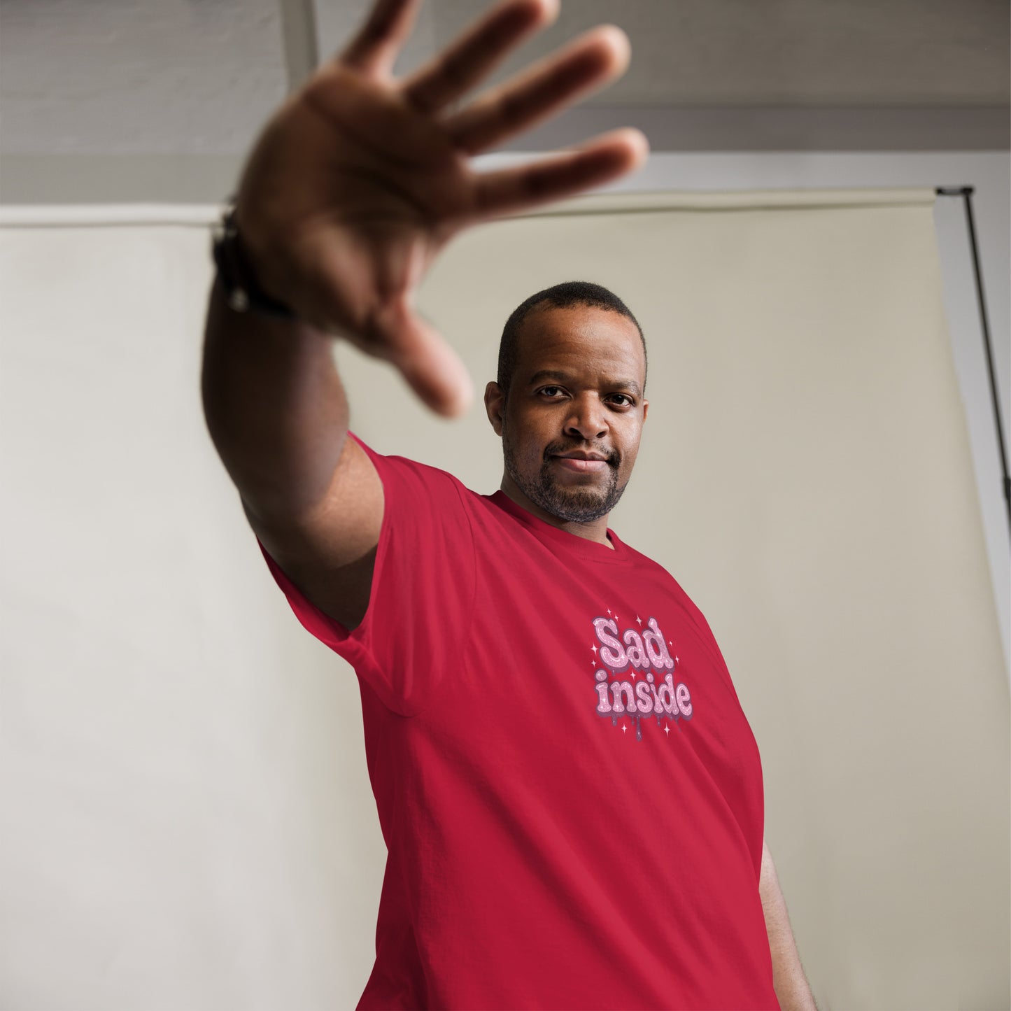 Man wearing a red t-shirt with 'Say it. Inside' text, gesturing with his hand.