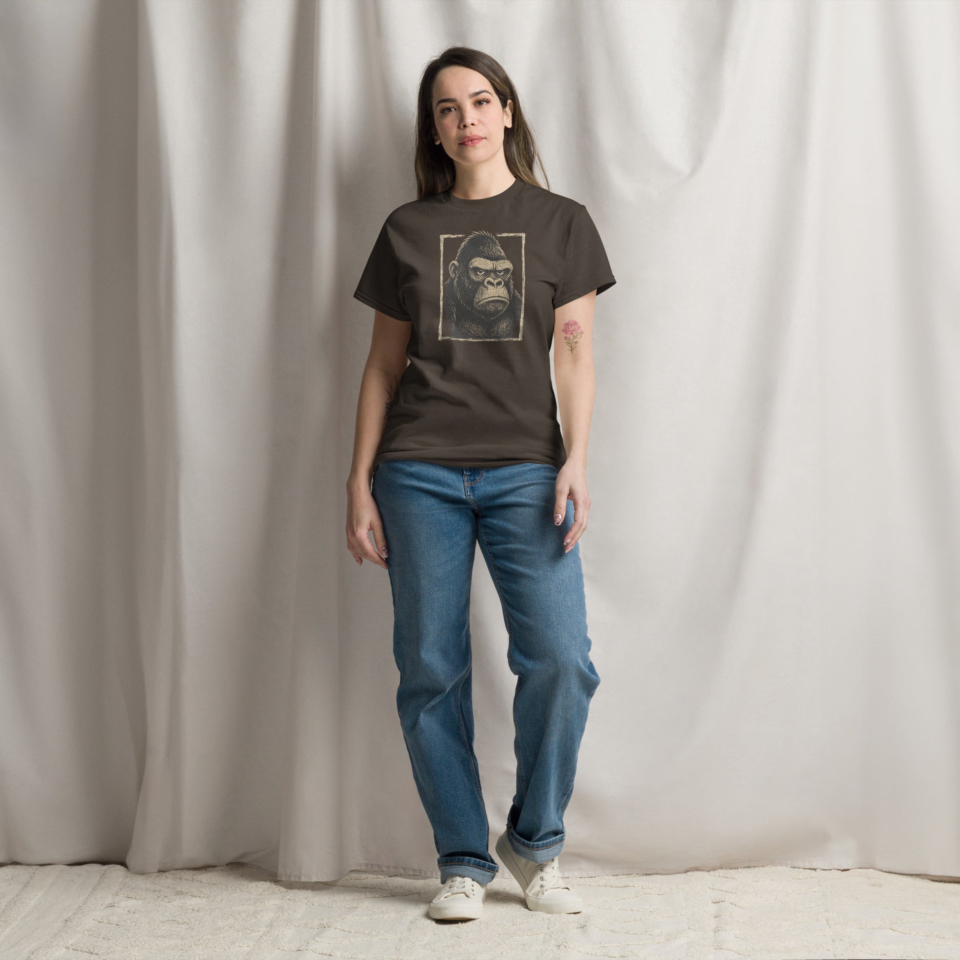 Person wearing a dark t-shirt with a graphic design of a gorilla and blue jeans against a plain background