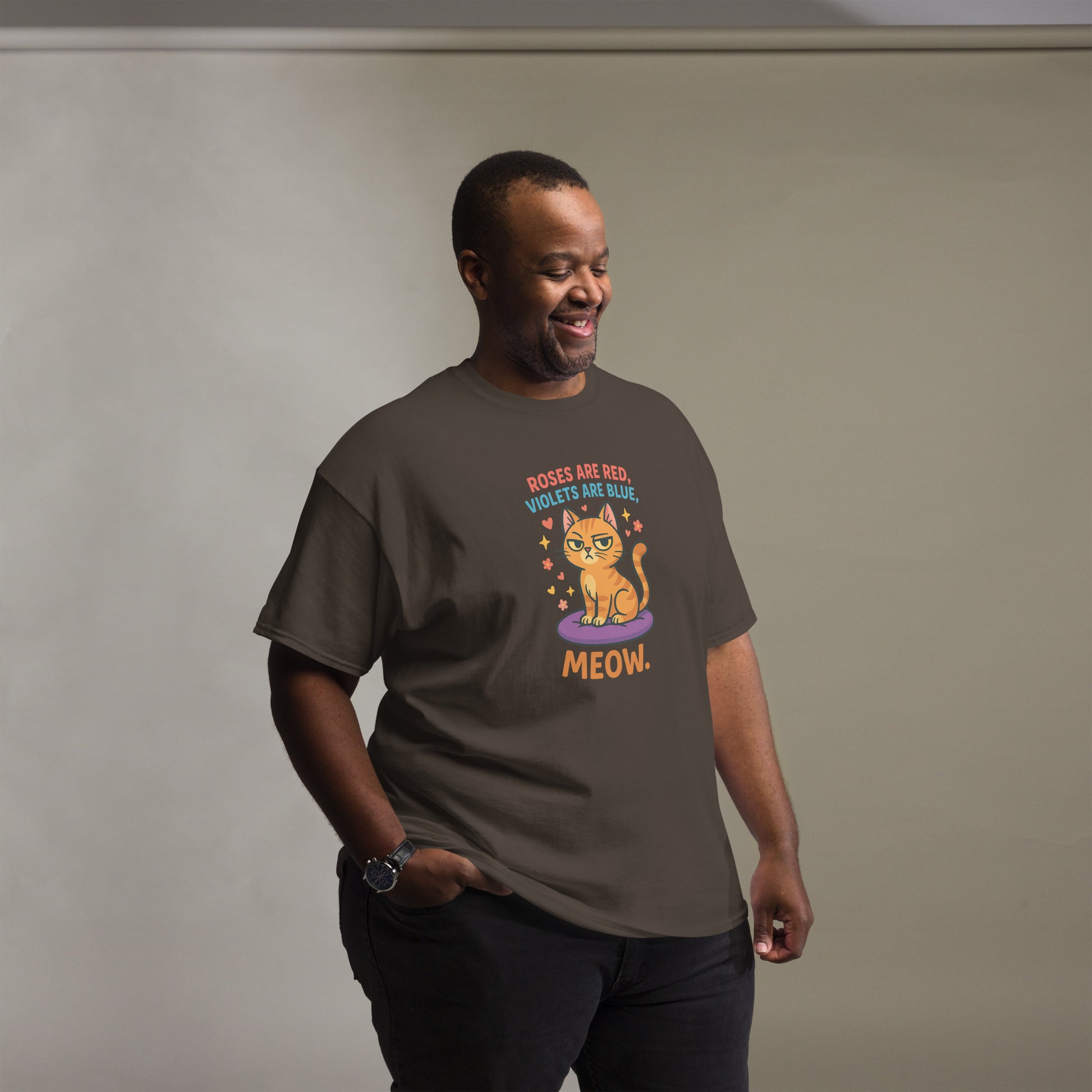 Man wearing a brown t-shirt with a cat graphic and text against a plain background