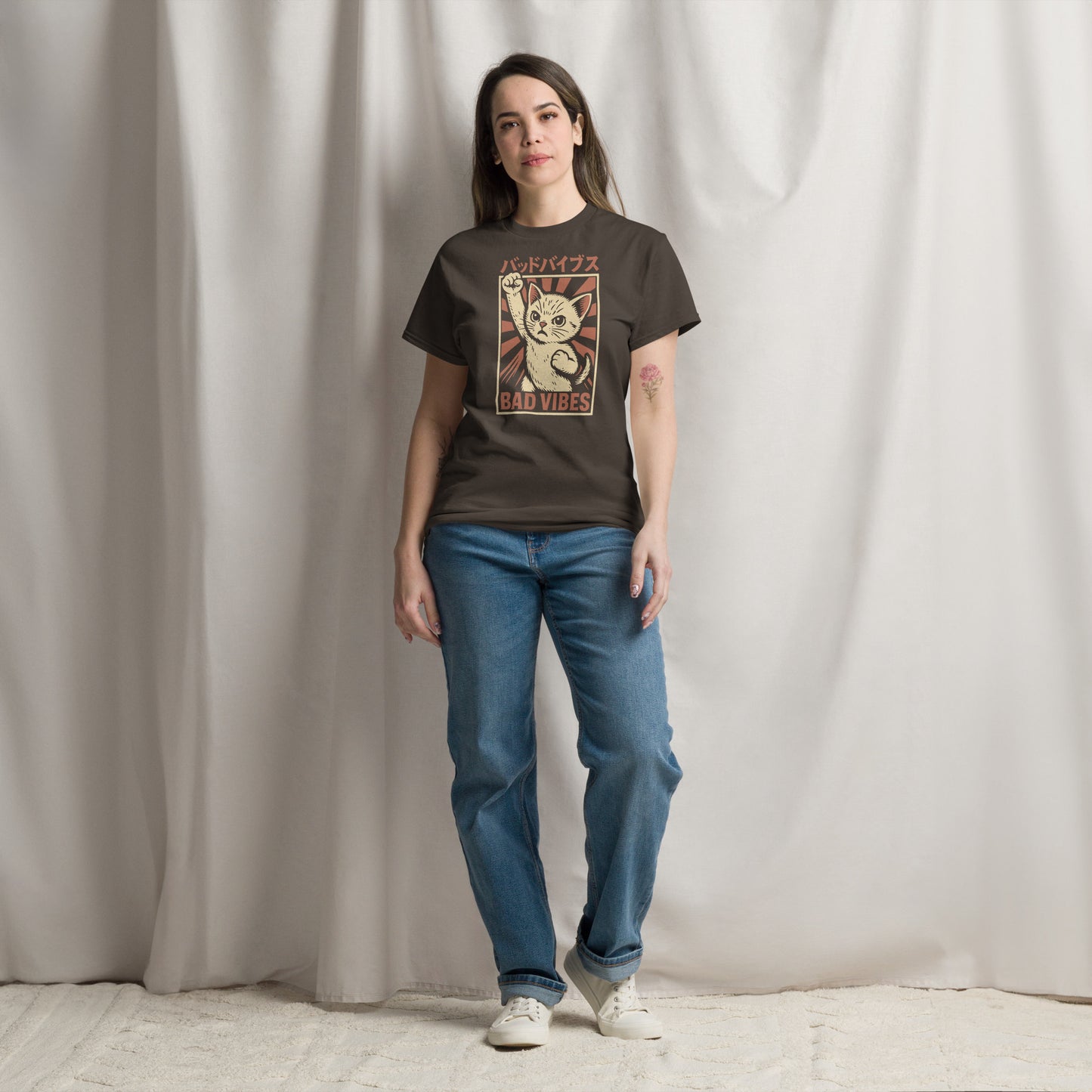 Person wearing a graphic t-shirt and blue jeans standing against a plain background
