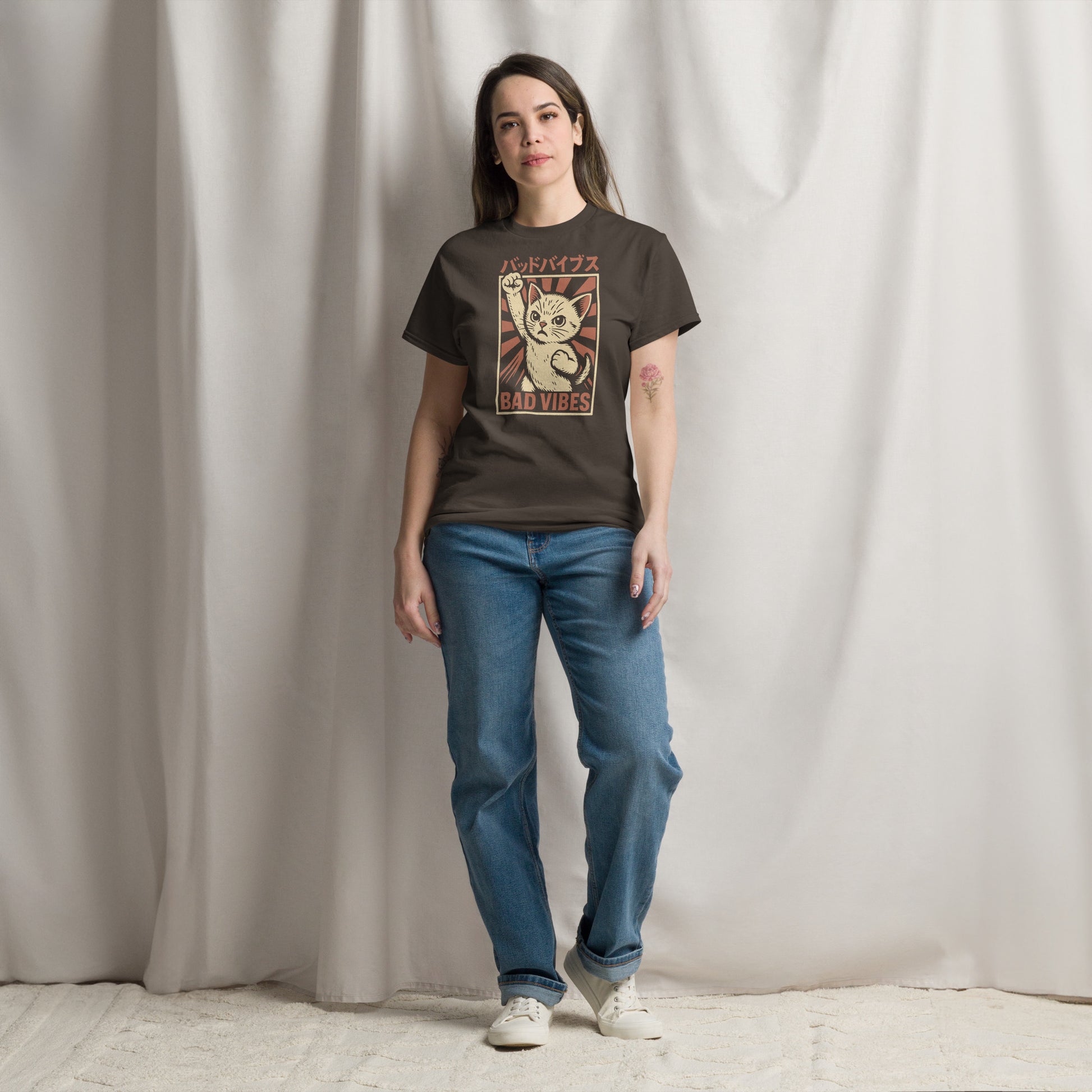 Person wearing a graphic t-shirt and blue jeans standing against a plain background