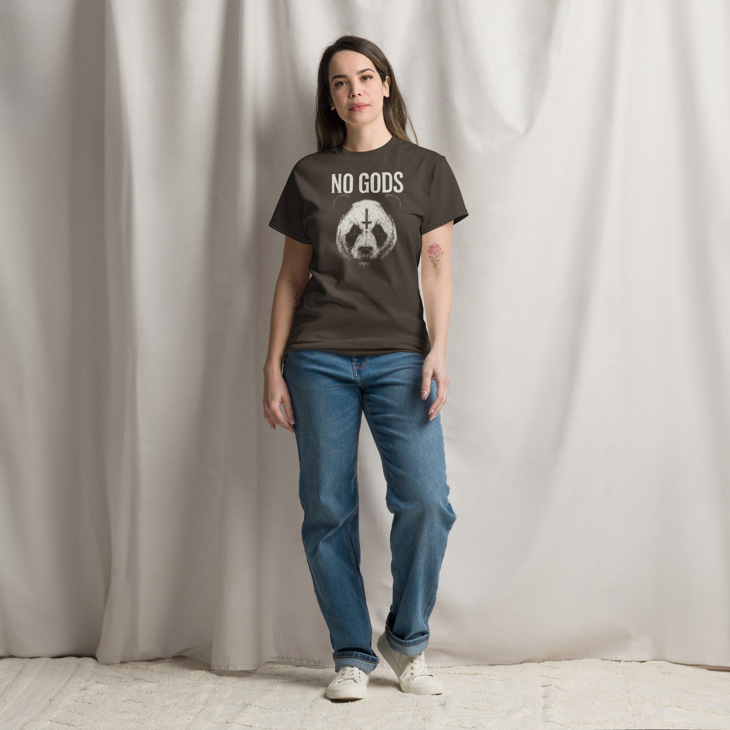 Person wearing a t-shirt with 'NO GODS' text and graphic, standing against a plain background