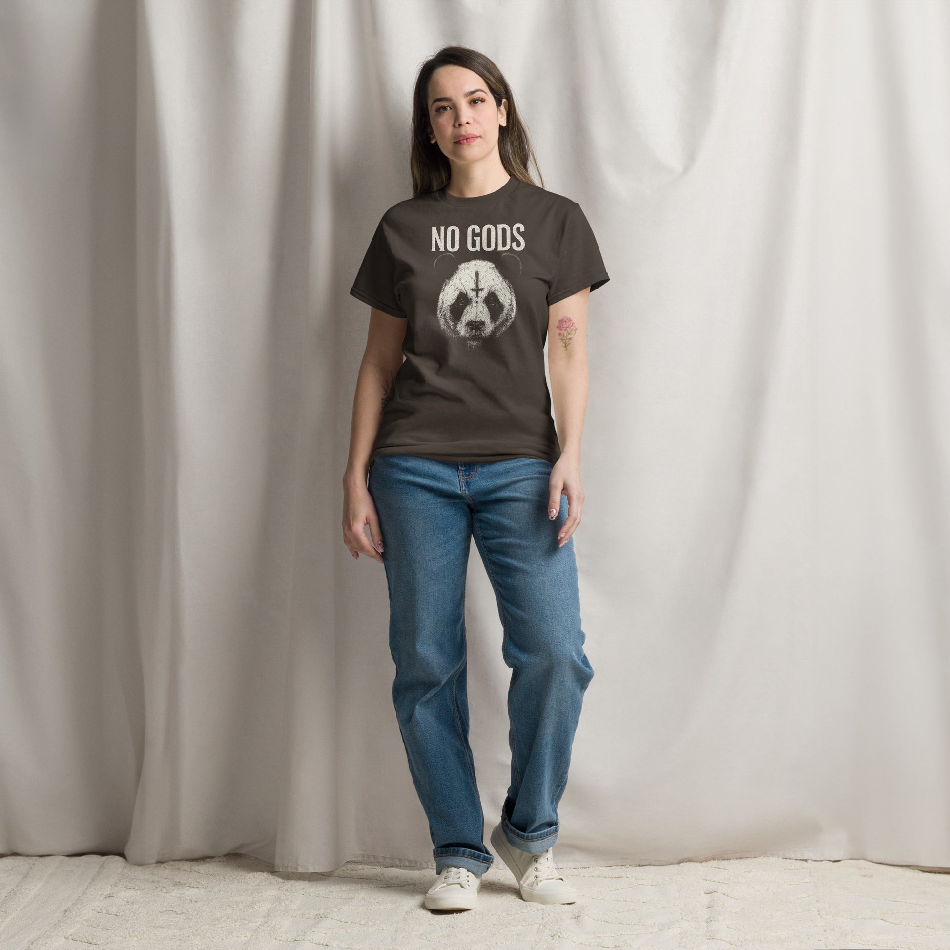 Person wearing a t-shirt with 'NO GODS' text and graphic, standing against a plain background