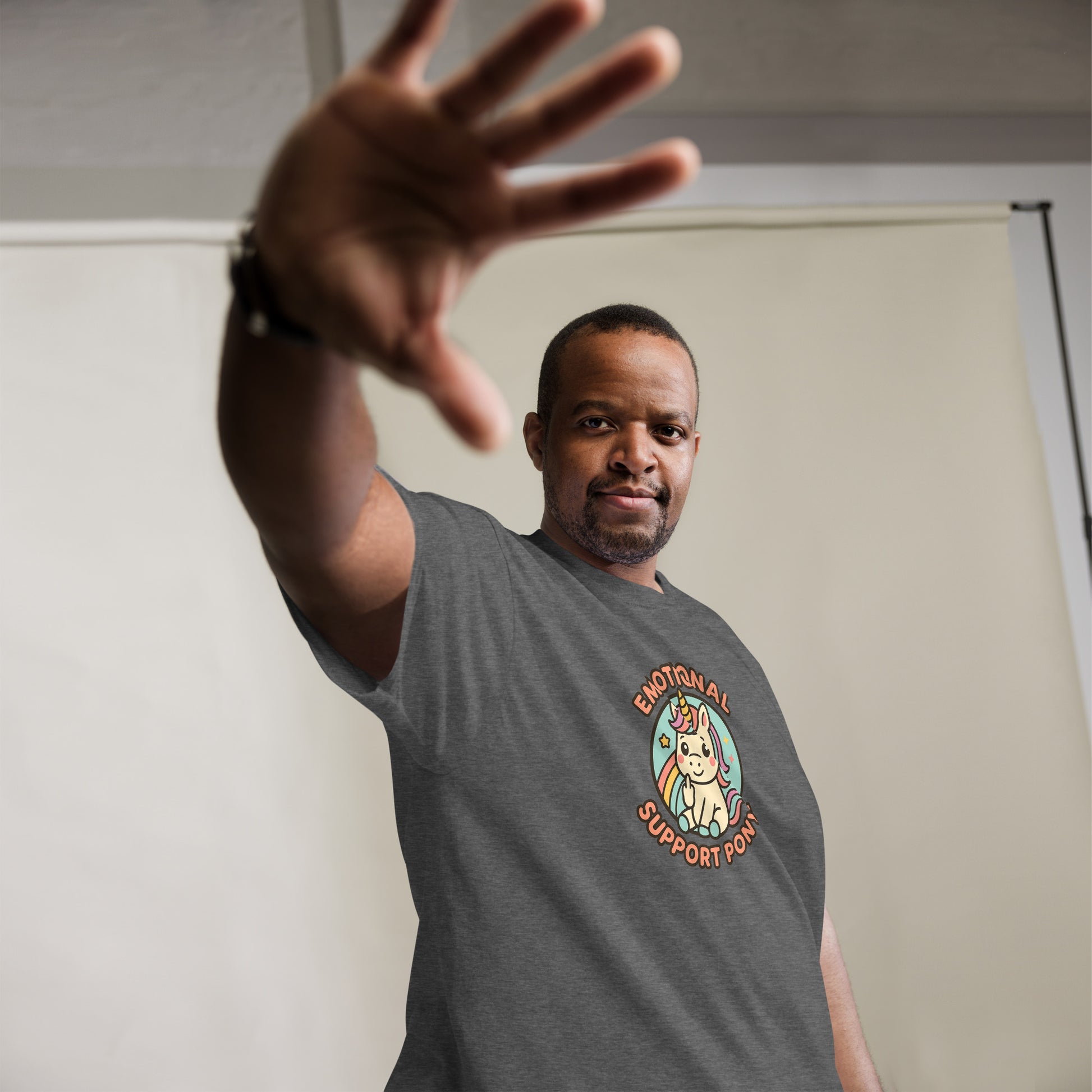 Man wearing a gray t-shirt with a colorful graphic and text, standing against a plain background.