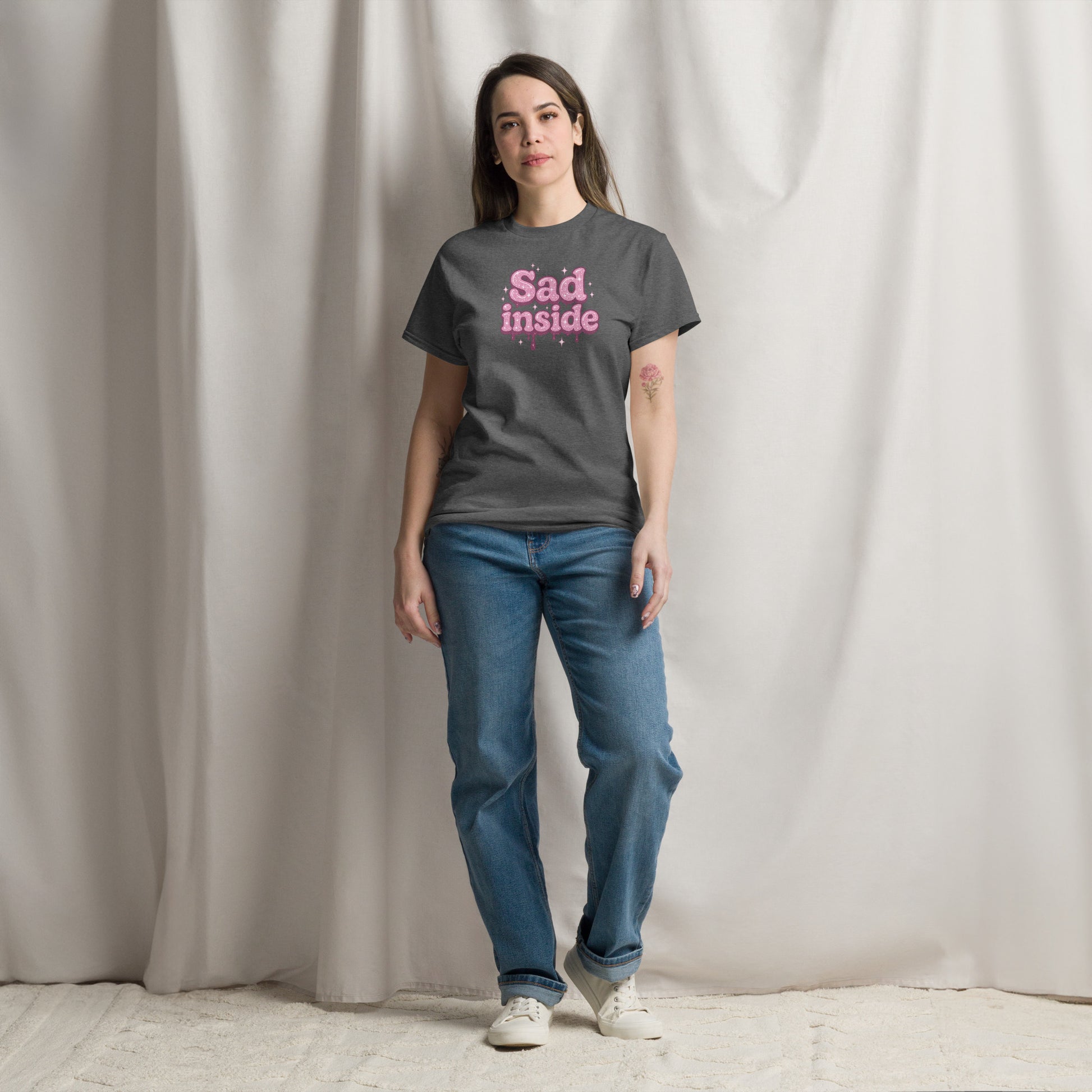 Person wearing a dark gray t-shirt with 'Sad inside' text in pink, standing against a plain background.