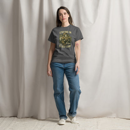 Person wearing a gray t-shirt with a graphic and text, standing against a plain background