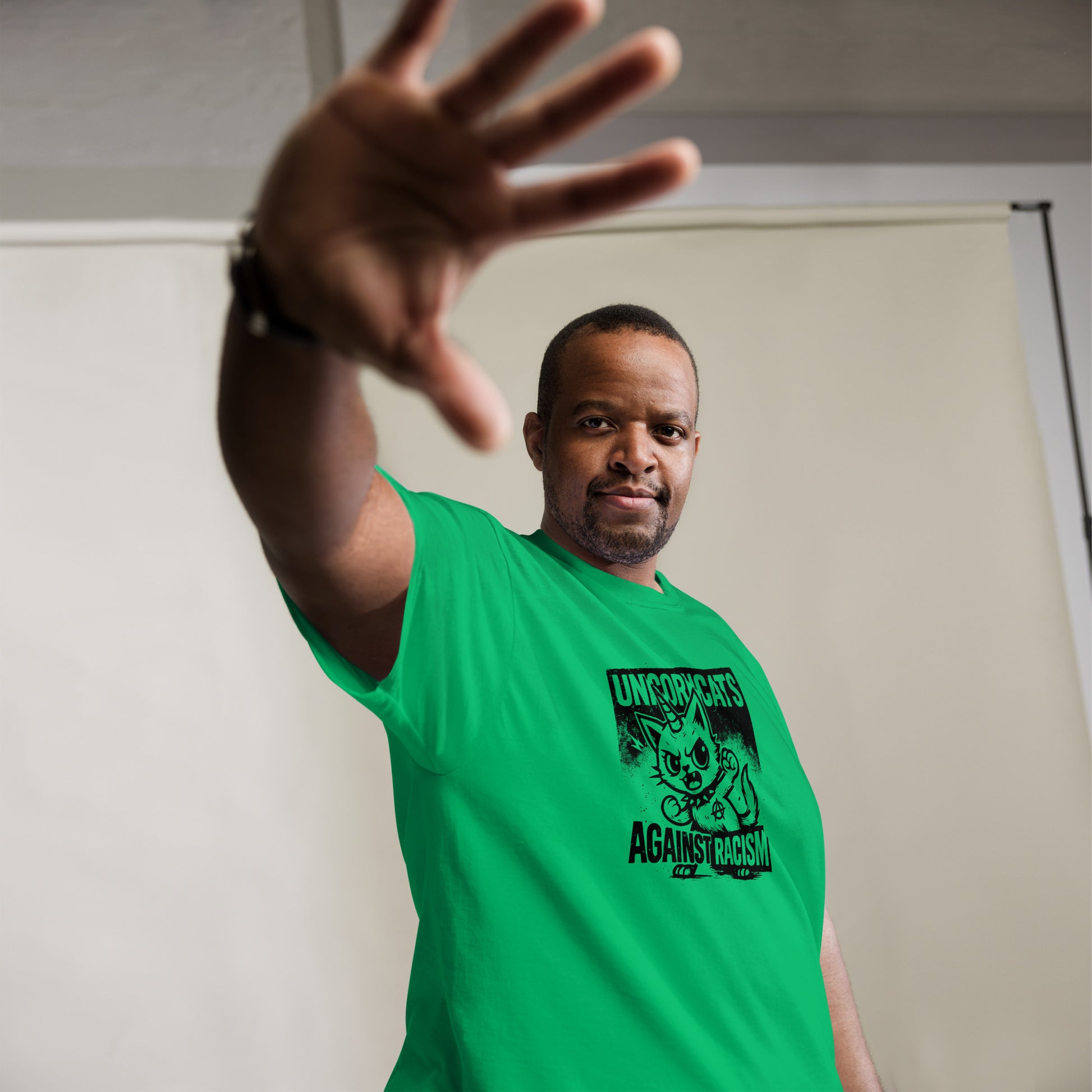 Person wearing green shirt with a unicorncat and the slogan "Unicorncats against racism"