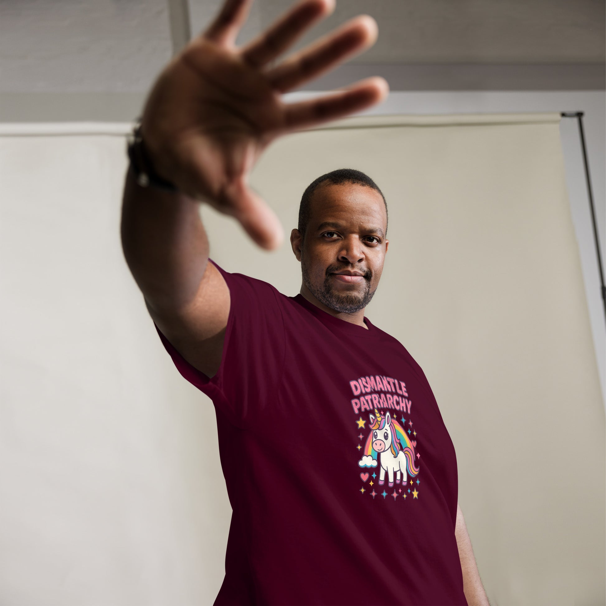Man wearing a maroon t-shirt with a unicorn graphic and text, standing against a plain background.