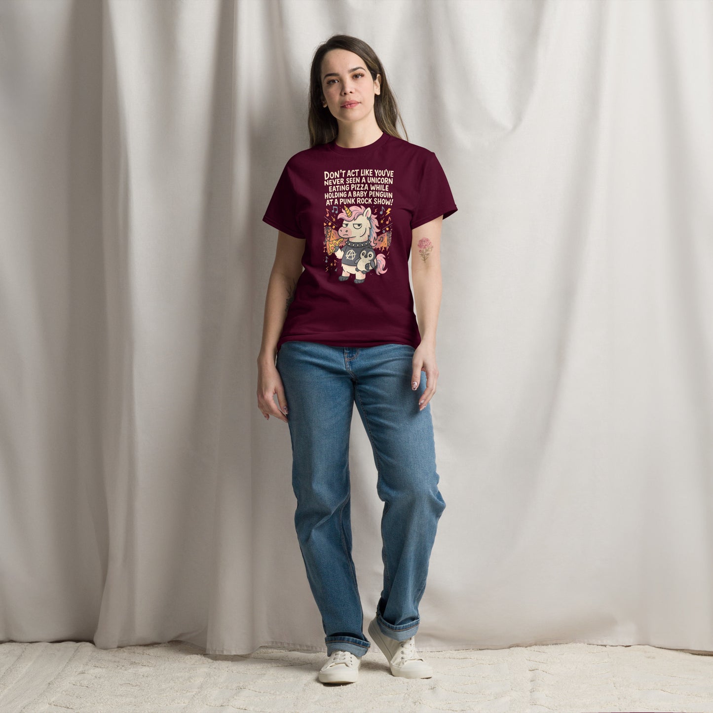 Person wearing a maroon t-shirt with a graphic design against a plain background