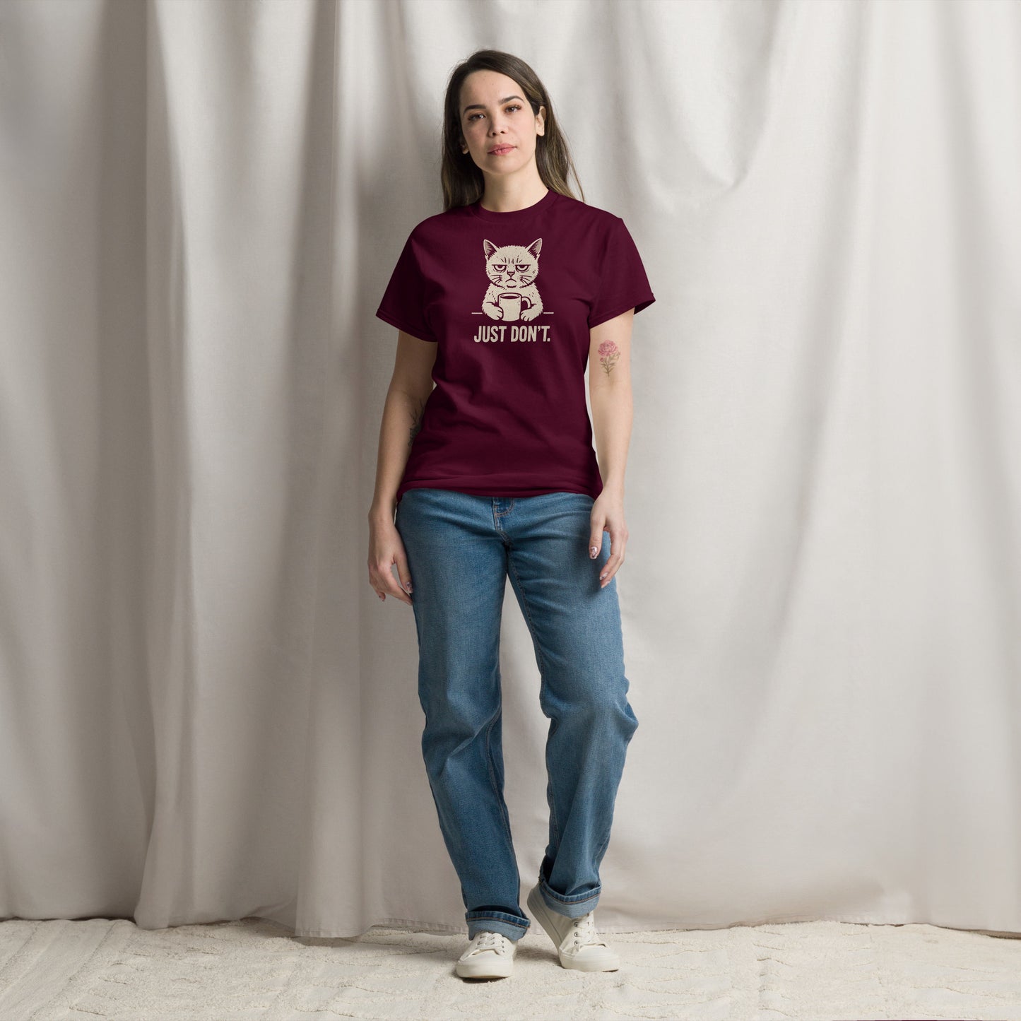 Person wearing a maroon t-shirt with a graphic and text, standing against a plain background