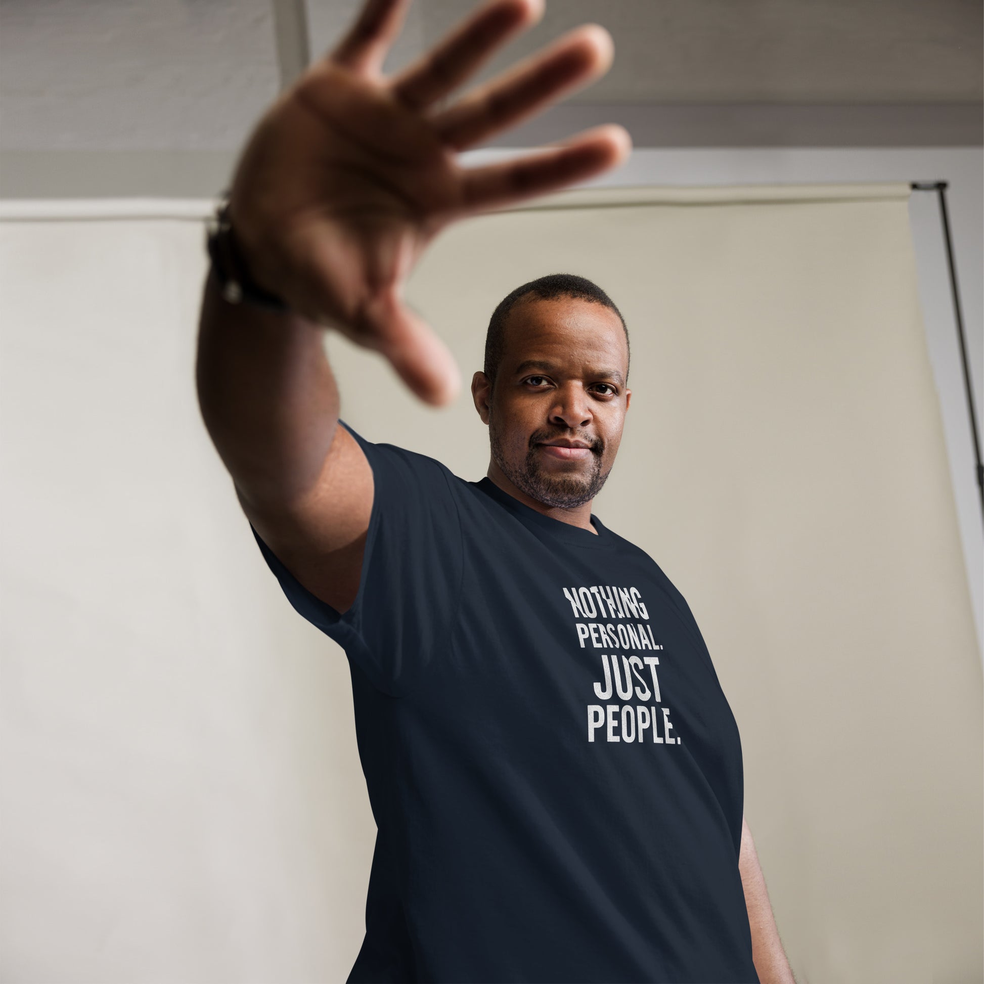 Man wearing a black t-shirt with 'Nothing Personal Just People' text, reaching out with his hand.