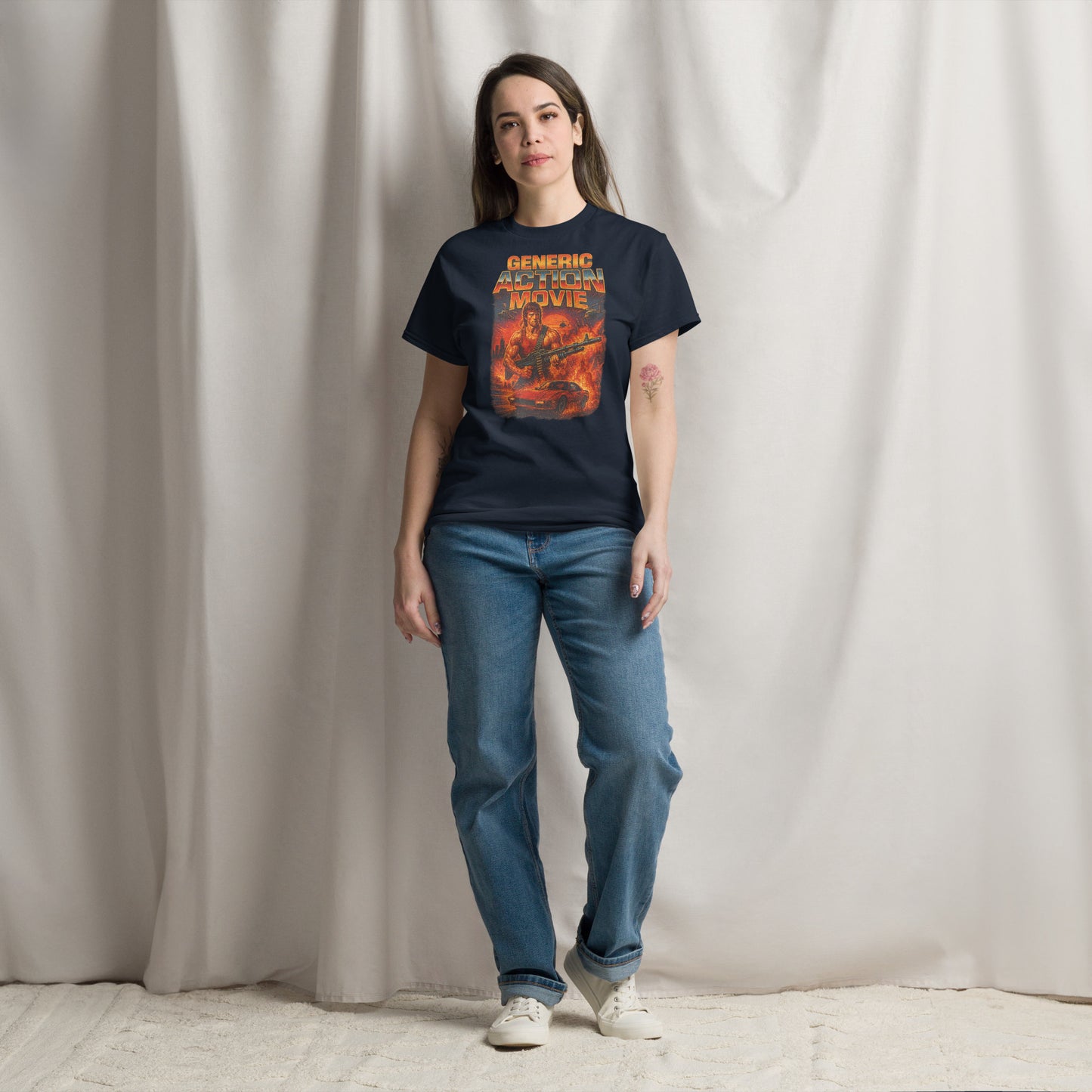 Person wearing a navy blue t-shirt with a graphic design and blue jeans against a plain background