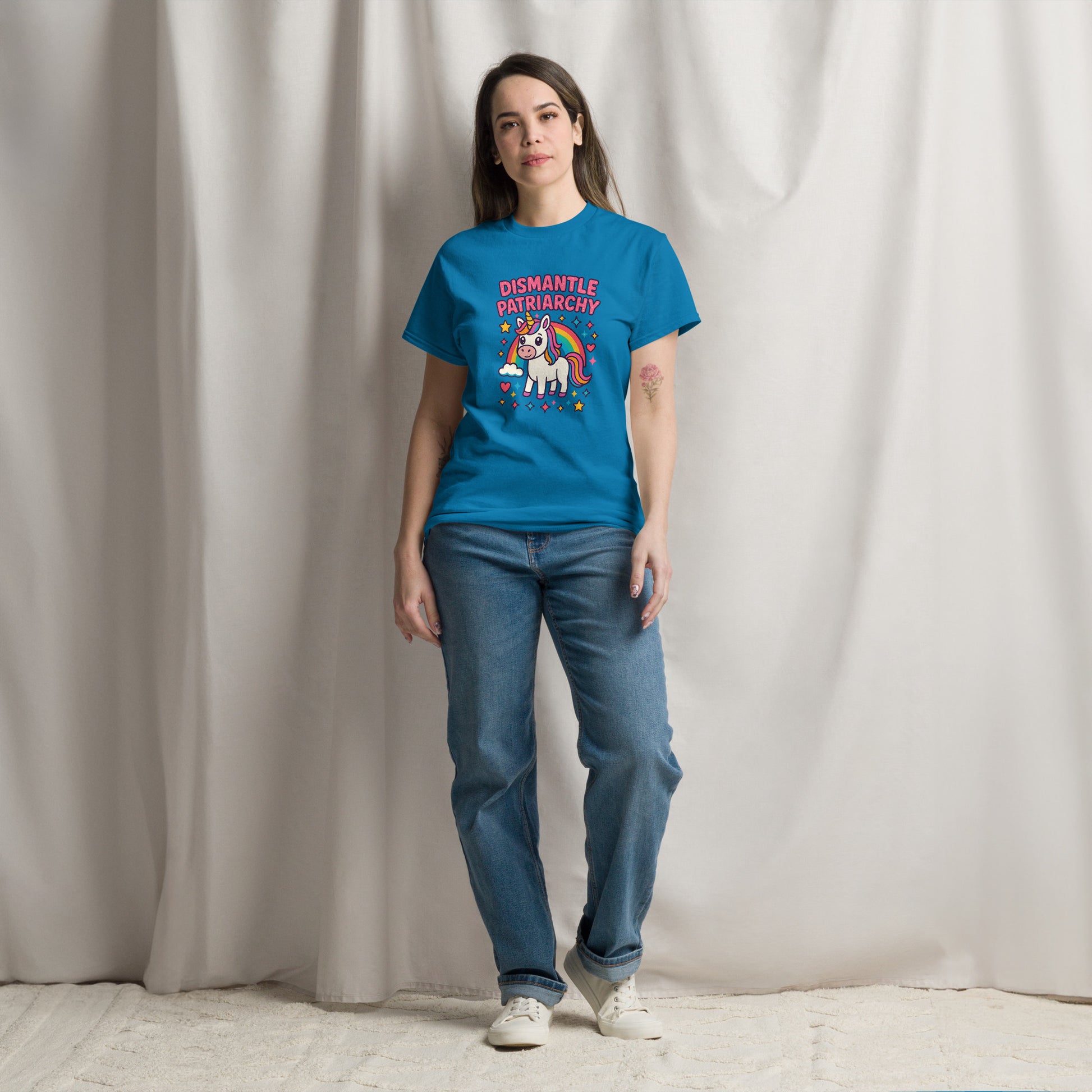 Person wearing a blue t-shirt with a graphic design and text, standing against a plain background