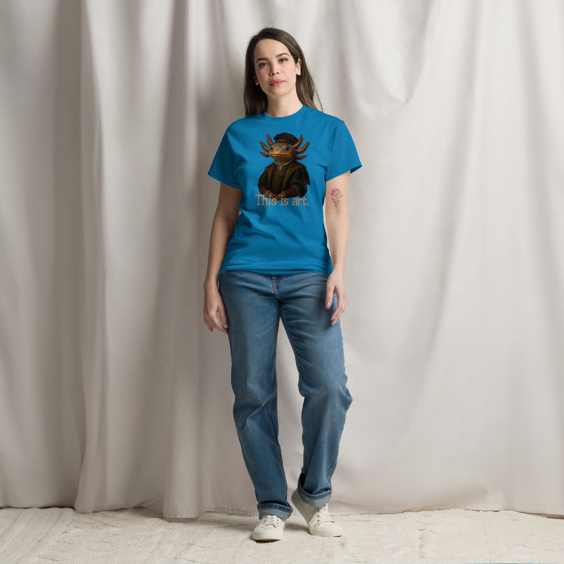 Person wearing a blue t-shirt with a graphic design and text, standing against a plain background