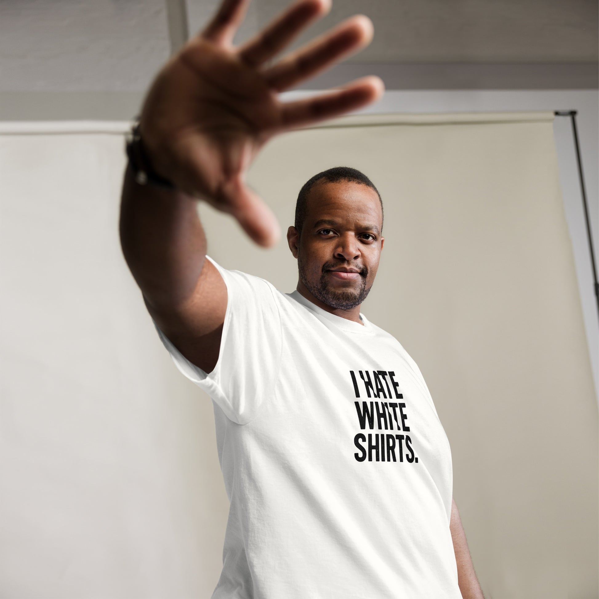 Man wearing a white t-shirt with text, making a stop gesture.
