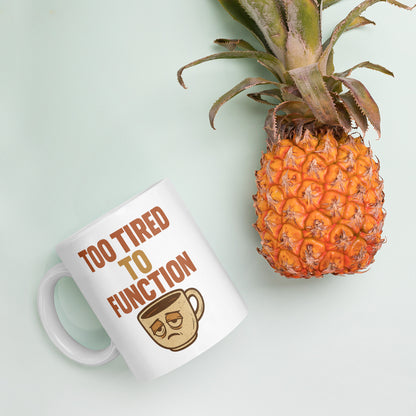 White mug with 'Too Tired to Function' text and a pineapple on a light green background