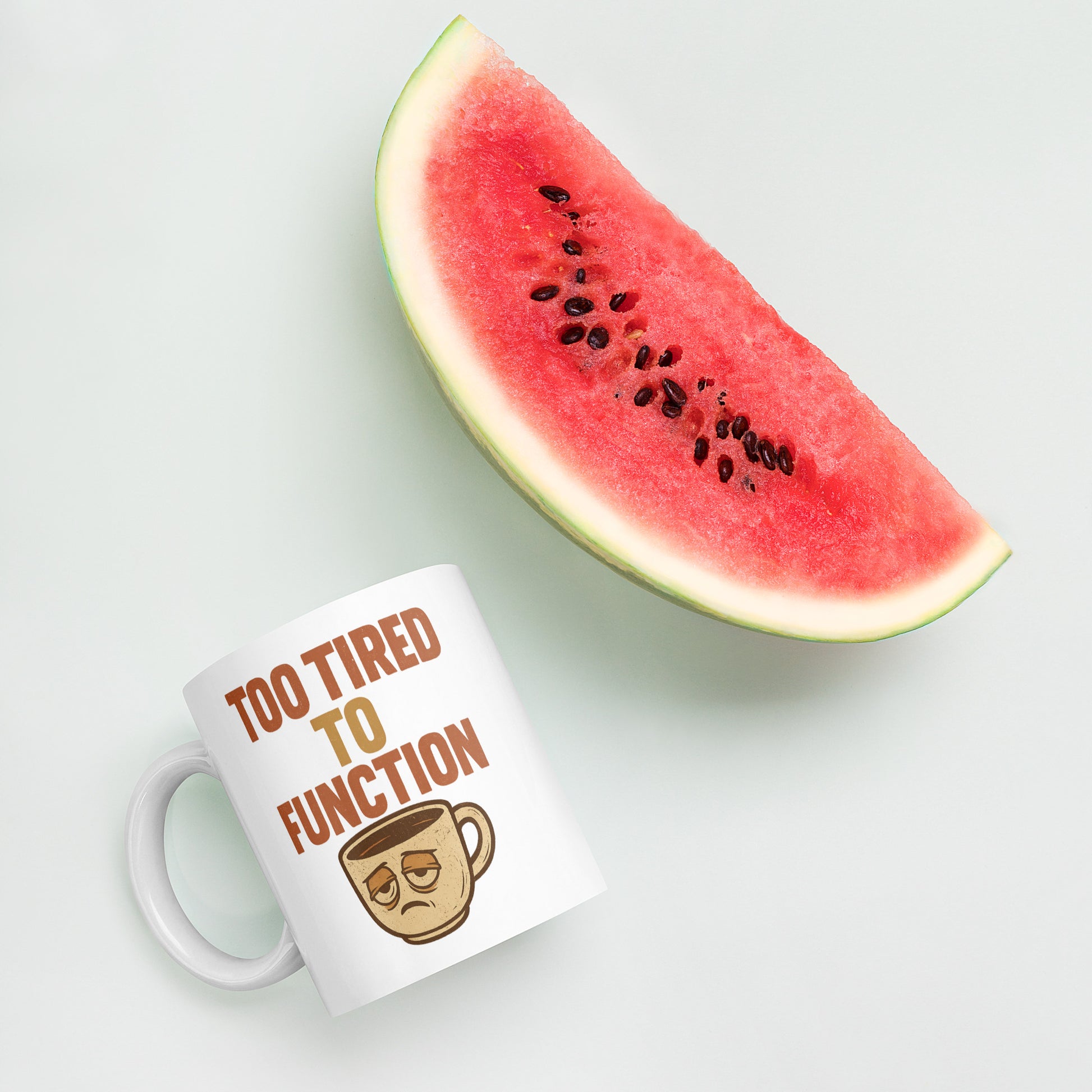 Mug with 'Too Tired to Function' text and a watermelon slice on a light background